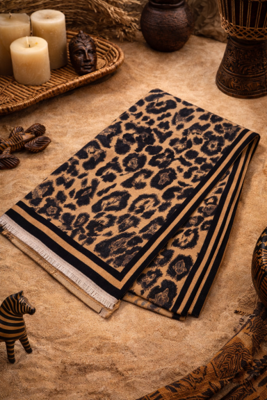 Serviette avec motif léopard sur un fond beige, décorée de bougies et d'objets en terre cuite.