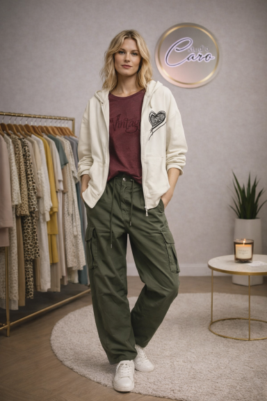 Femme en sweat à capuche et pantalon large, posant dans un décor moderne et lumineux.