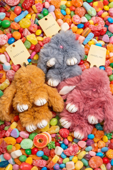 Trois peluches en forme de pattes de lapin sur un lit de bonbons colorés.