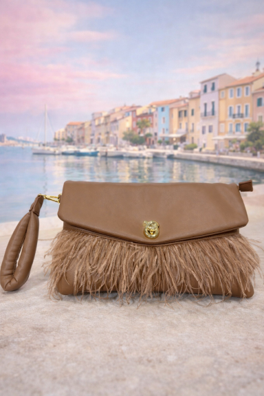 Sac à main beige avec franges, devant un port et des maisons colorées.