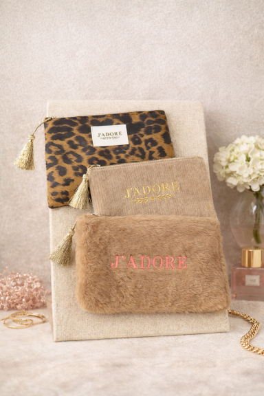 Trois pochettes en tissu, deux avec motifs et une en fausse fourrure, décorées de franges.